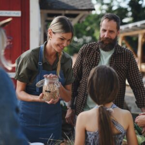 Little girl with her mother buying organic vegetables outdoors at community farmers market